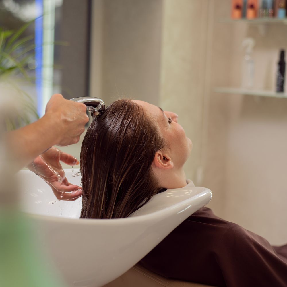Se ve una chica en una peluquería, sentada mientras le lavan el cabello.